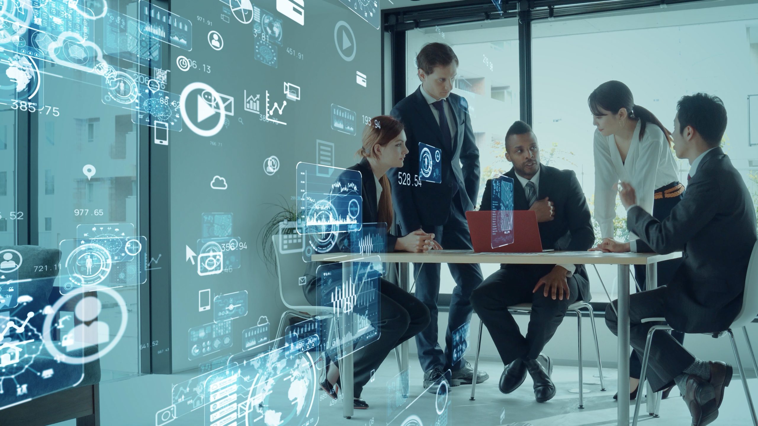 Business team collaborating around a table with a laptop, surrounded by digital data overlays and analytics icons in a modern office setting.